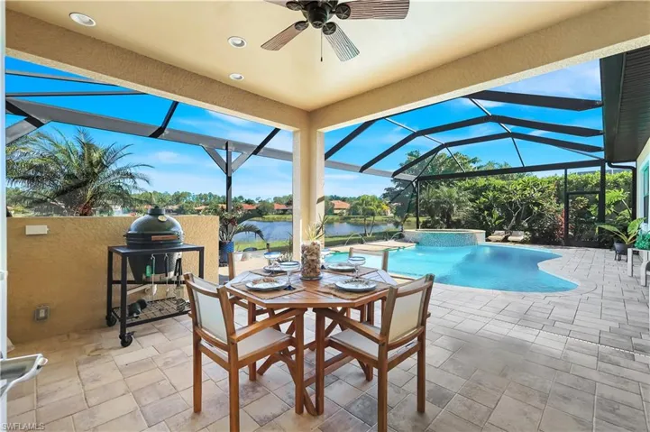 Outdoor pool with glass enclosure, a sunroom, a patio, ceiling fan, and grilling area