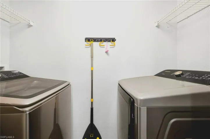 Dedicated laundry area featuring wire shelving and stainless-steel appliances