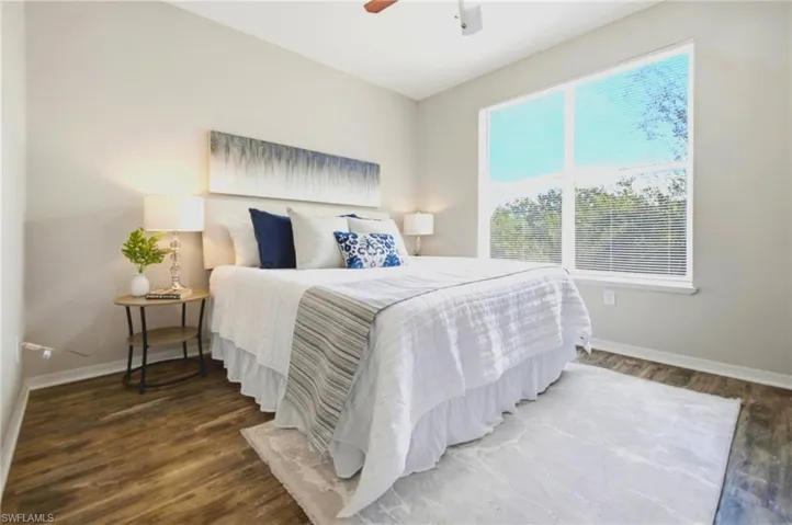 Neutral-toned walls, wood-finish flooring, large window with integrated blinds, and ceiling fan