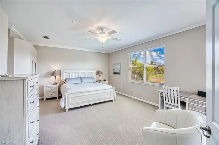 Carpeted bedroom with ceiling fan and crown molding
