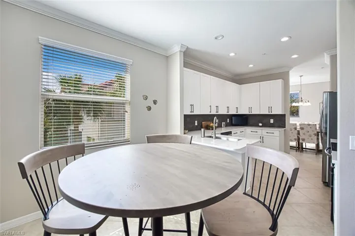 Kitchen featuring tasteful backsplash, sink, light tile patterned floors, decorative light fixtures, and white cabinets