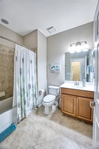 Full bathroom with tile patterned floors, vanity, shower / tub combo, and toilet