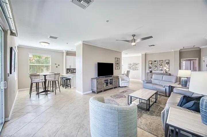 Tiled living room with ceiling fan and ornamental molding
