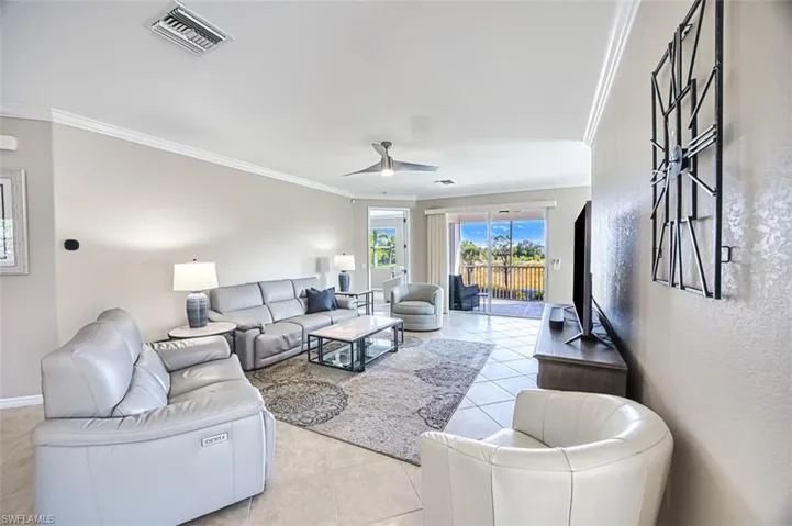 Living room with ceiling fan, light tile patterned floors, and crown molding