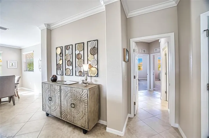 Corridor featuring crown molding and light tile patterned floors