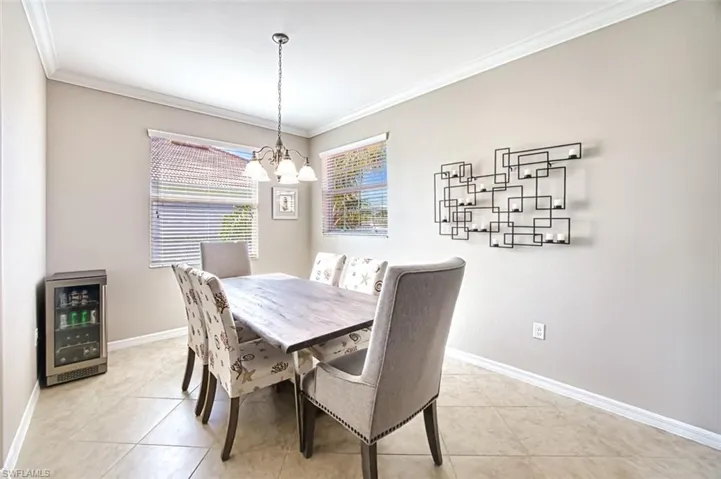 Tiled dining area featuring a notable chandelier, crown molding, and beverage cooler