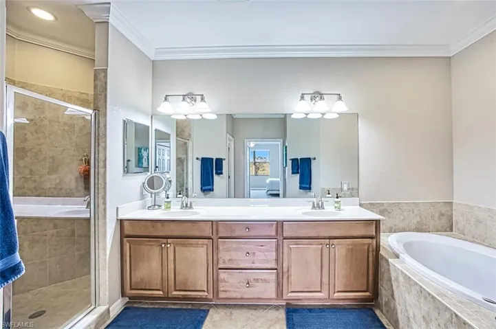 Bathroom with plus walk in shower, vanity, tile patterned floors, and ornamental molding