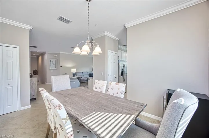 Dining space featuring a chandelier, light tile patterned floors, and ornamental molding