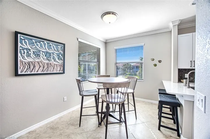 Dining room with sink, ornate columns, ornamental molding, and light tile patterned flooring