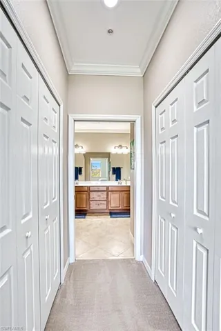 Corridor featuring crown molding and light colored carpet