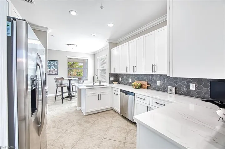 Kitchen with sink, light stone counters, kitchen peninsula, white cabinets, and appliances with stainless steel finishes