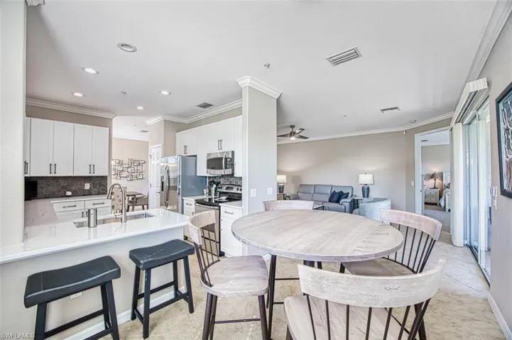 Tiled dining space featuring ceiling fan, crown molding, and sink