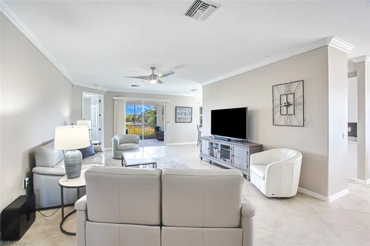 Tiled living room with ceiling fan and crown molding