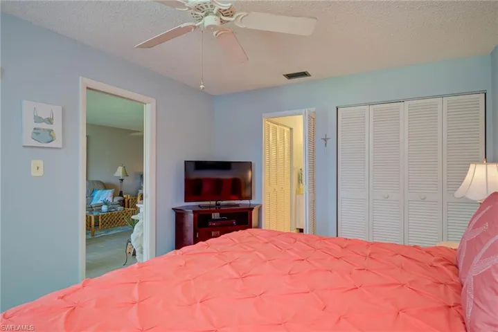 Bedroom with two closets, a textured ceiling, and a ceiling fan