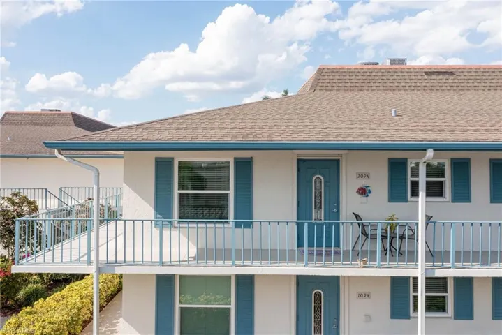 View of front of home with a shingled roof, stucco siding, and a balcony