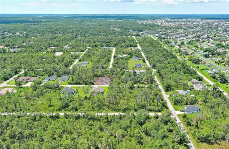 Aerial view of property and surrounding area with a forest