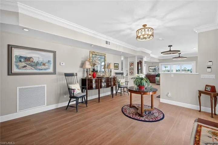 Living area featuring crown molding, light wood-style floors, and a chandelier