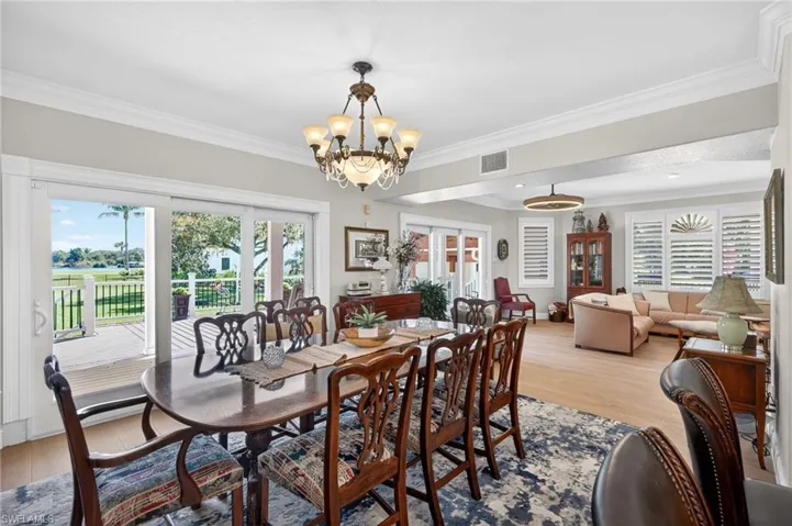 Dining room with ornamental molding, light wood-style floors, healthy amount of natural light, a chandelier, and french doors