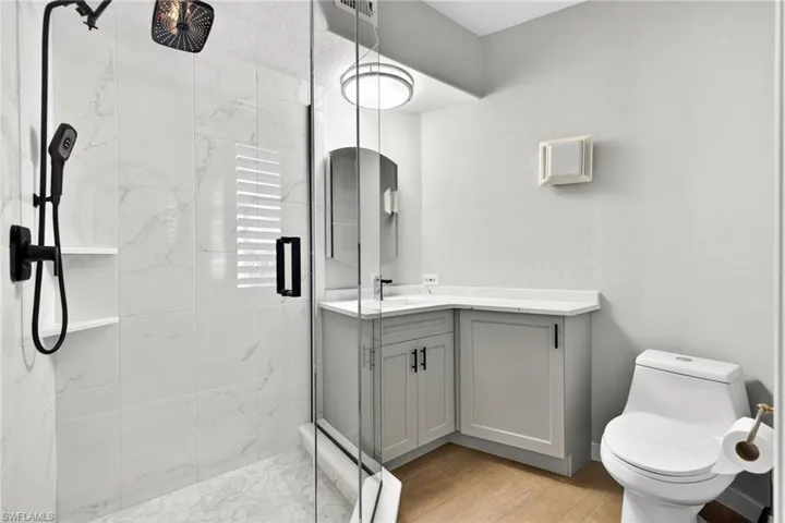 1st Level Bathroom featuring vanity, a marble finish shower, and a textured wall