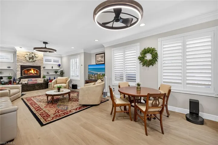Family room featuring a stone fireplace, light wood-type flooring, recessed lighting, crown molding, and ceiling fan
