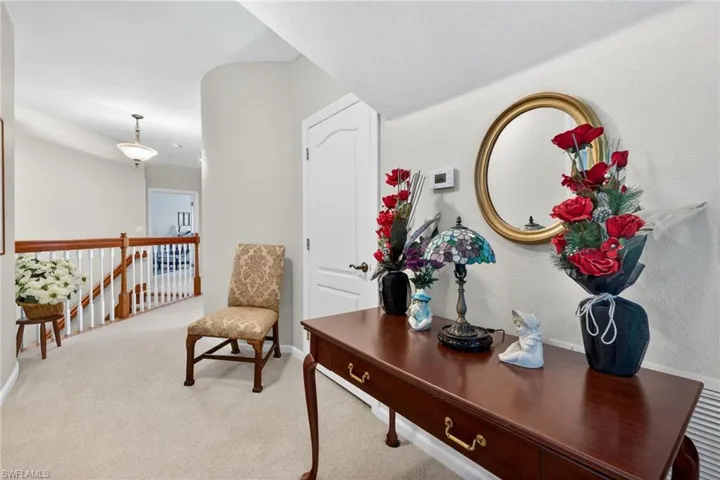 Corridor with an upstairs landing and light carpet