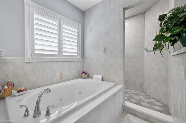2nd level Primary Bath with tile walls, a walk in shower, and a jetted tub