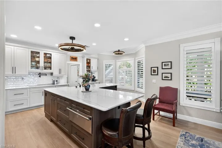 Dual tone kitchen with dual tone cabinets, glass insert cabinets, Quartz countertops, a warming drawer, and a center island