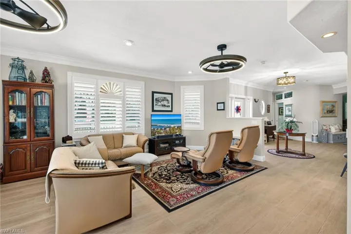Living room featuring ceiling fan, crown molding, light wood-style floors, and recessed lighting