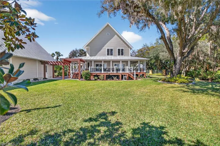 Back of property with a lawn, covered porch