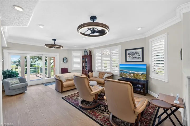 Living area with plenty of natural light, ornamental molding, light wood-type flooring, recessed lighting, and a ceiling fan