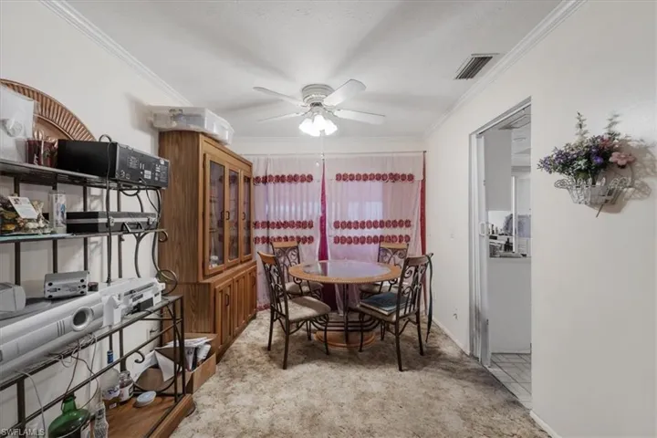 Dining room with crown molding, light carpet, and a ceiling fan