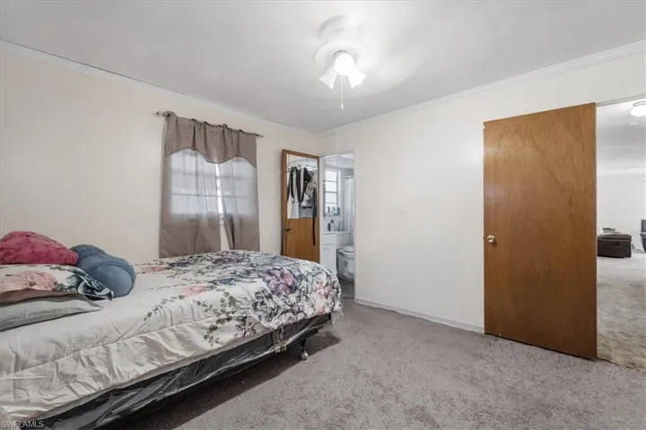 Bedroom with carpet flooring, crown molding, a ceiling fan, and ensuite bathroom