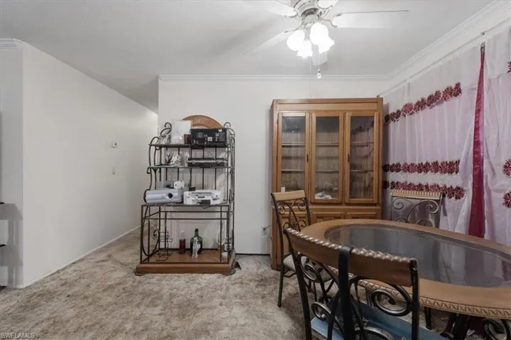Dining area with light colored carpet, crown molding, and a ceiling fan