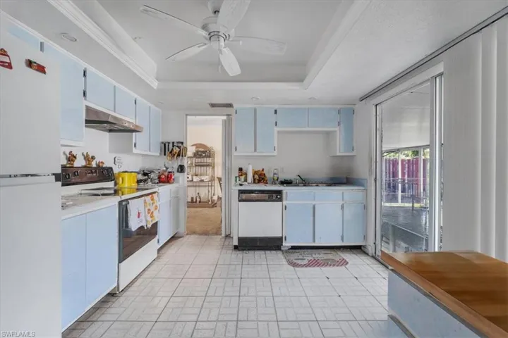 Kitchen featuring white appliances, light countertops, brick patterned floors, ceiling fan, and under cabinet range hood