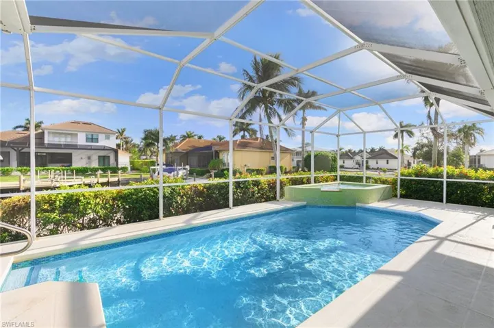 View of pool with screen enclosure and a patio area
