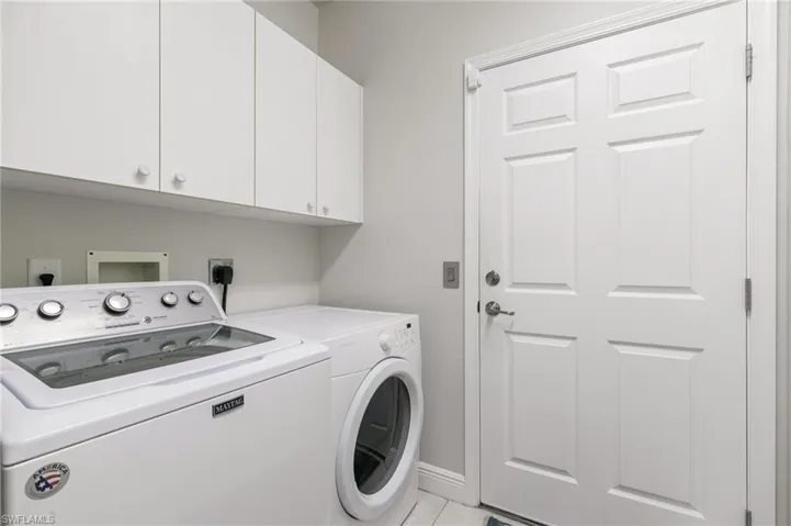Laundry room featuring light tile floors, cabinets, and independent washer and dryer