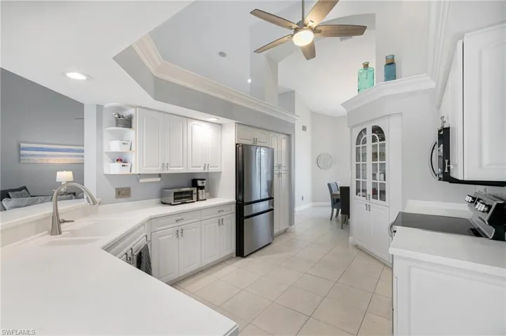 Kitchen with appliances with stainless steel finishes, ceiling fan, crown molding, sink, and white cabinets