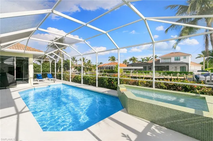 View of pool with screen enclosure and a patio area