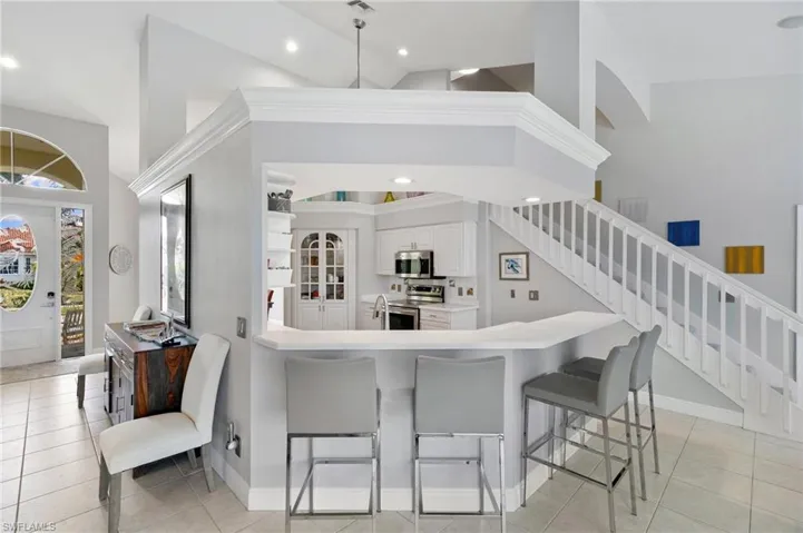 Kitchen featuring white cabinetry, stainless steel appliances, a kitchen breakfast bar, high vaulted ceiling