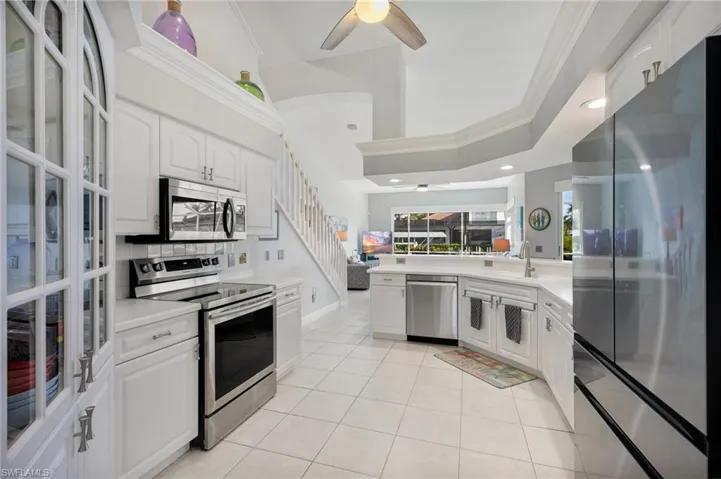Kitchen with ceiling fan, white cabinets, and stainless steel appliances