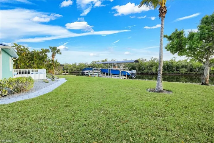 View of grassy yard featuring a water view, a boat dock, and boat lift