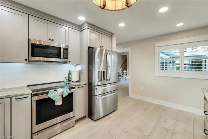 Kitchen featuring stainless steel appliances, light wood finished floors, recessed lighting, backsplash, and light stone countertops