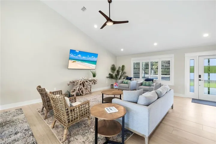 Living room with a ceiling fan, light wood-style floors, vaulted ceiling, and recessed lighting