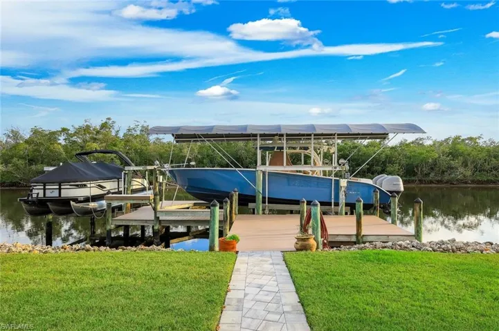 Dock area featuring boat lift, a water view, and a lawn