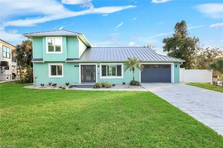 View of front facade featuring a standing seam roof, stucco siding, concrete driveway, and an attached garage