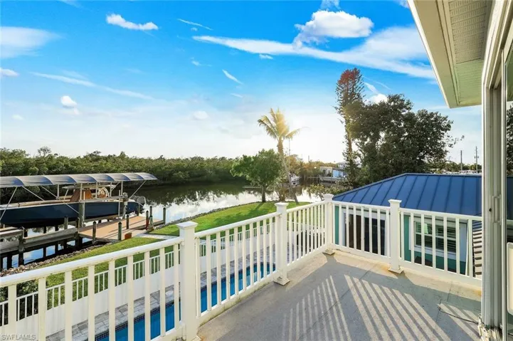 Balcony with view of pool, boat lift, a water view, and a dock