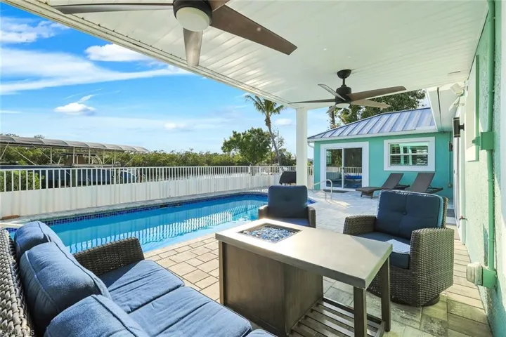 View of pool with patio surround, an outdoor living space with a fire pit, and a fenced backyard