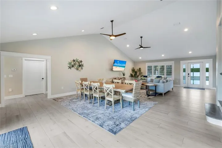 Dining space with a high ceiling, light wood-style flooring, recessed lighting, and a ceiling fan