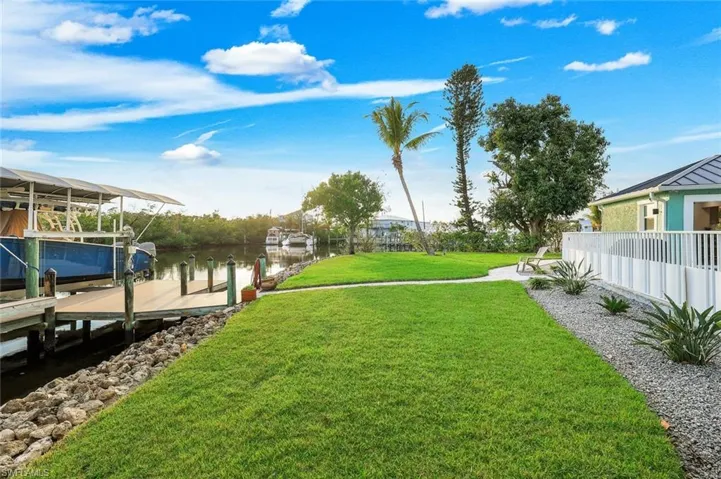 View of grassy yard featuring a water view, a dock, and boat lift