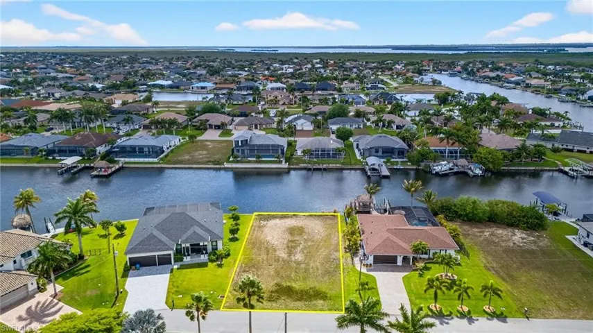 Aerial perspective of suburban area with property boundaries highlighted and a large body of water